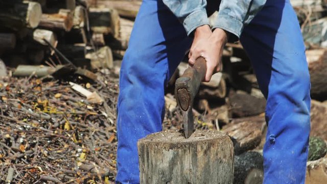 Chopping wood slow motion. Worker in blue overalls chopping wood outdoors