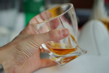 Male hand holding a whiskey glass with golden liquor as a symbol of drinking alcohol