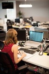 Businesswoman holding coffee cup while working in office