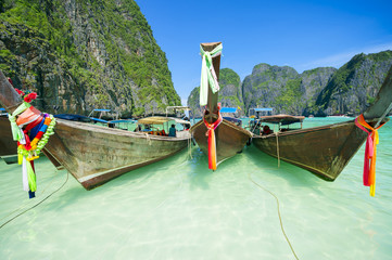 Traditional Thai wooden longtail boats with colorful sashes in the turquoise Andaman waters of Maya Bay, in Southern Thailand
