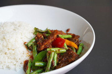 Closeup a plate of Stir-fried red chillies paste, ginger with deep fried catfish and cow-pea served with steamed rice.