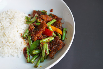 Closeup a plate of Stir-fried red chillies paste, ginger with deep fried catfish and cow-pea served with steamed rice.