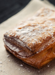 Puff pastry with powdered sugar on a piece of paper closeup shot, vertical
