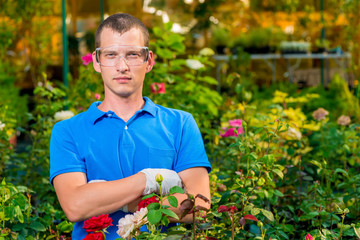 Man in glasses and laboratory gloves in a greenhouse among flowers