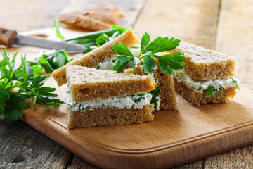 Simple cream cheese sandwiches with parsley and green onion on a table. Delicious healthy homemade snack.