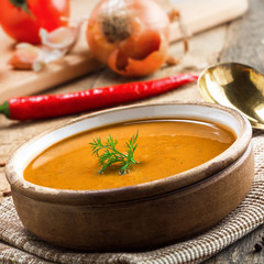 Healthy vegetarian lentil soup in a rustic clay bowl on an old wooden table. Delicious healthy meal served on a canvas tablecloth.