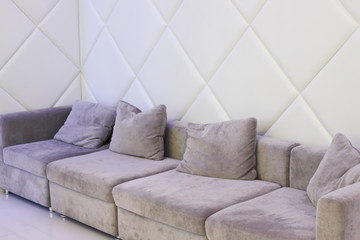 Fototapeta na wymiar Big grey couch with pillows is in white empty room for resting