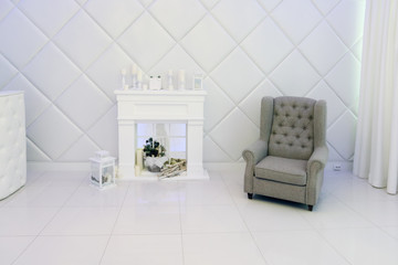 White room with decorative fireplace, candles, armchair, soft walls