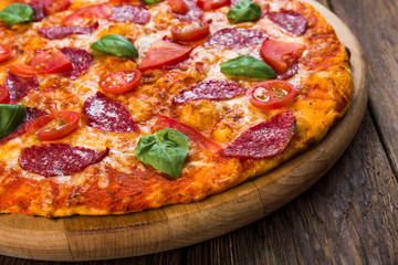 Delicious pizza with salami, closeup on wood