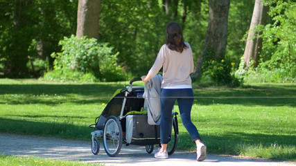 Frau mit Kinderwagen im Park