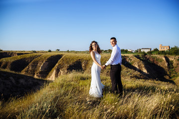 Beautiful couple in field, Lovers or newlywed posing on sunset with perfect sky