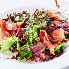 Restaurant food closeup - salad with prosciutto and vegetables