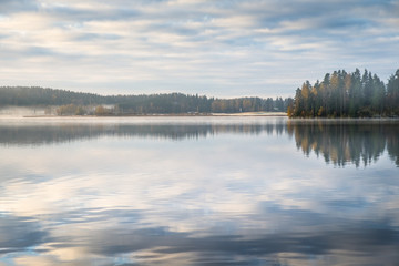 Scenic landscape with peaceful lake and fog at autumn morning