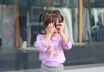 Portrait of cute little girl trying to wear glasses.