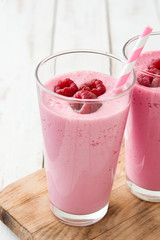 Raspberry smoothie in glass on white wooden table
