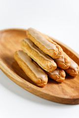 Eclairs on white background on wooden plate
