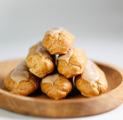 Eclairs on white background on wooden plate