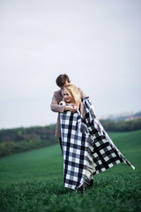 A man embraces a woman and covers her blanket