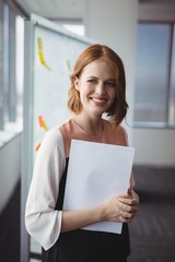Portrait of smiling executive holding documents