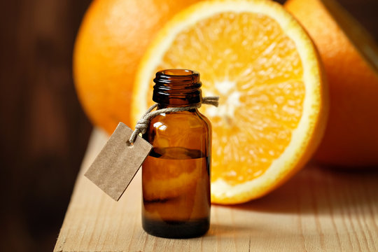 Orange essential oil in a glass bottle on a wooden table