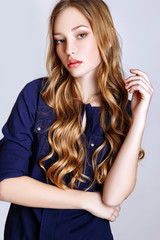 Fototapeta premium Fashion portrait of beautiful young woman with blond hair. Girl in a blue shirt and jeans on a white background