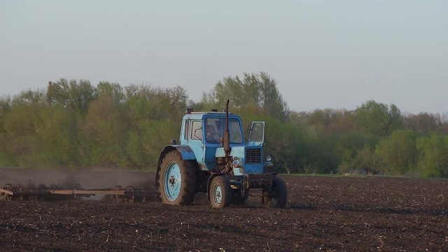Tractor Processing Field Farmer sowing a plowed field with old tractor