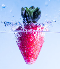 The strawberry falling in water, leaving splashes and bubbles