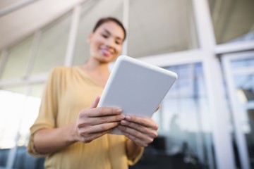 Fototapeta premium Low angle view of smiling businesswoman using tablet in office
