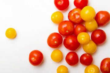 Red and yellow cherry tomatoes on a white background.