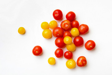 Red and yellow cherry tomatoes on a white background.