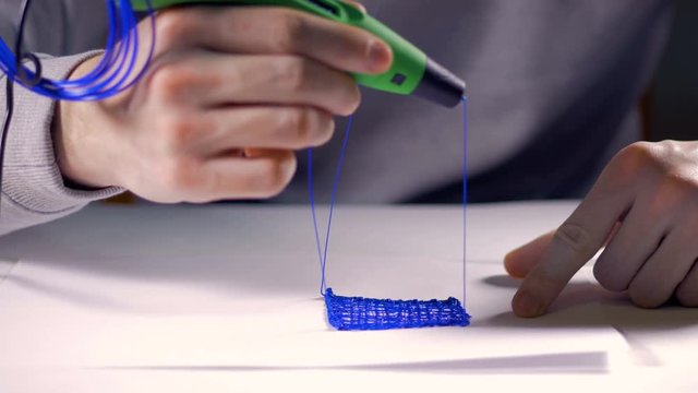 Creative man using 3d pen printing 3D shape.