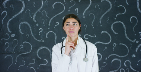 Portrait of a beautiful female doctor (student) thinking about choosing a profession, at a black...