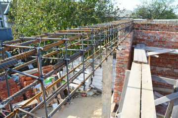 Unfinished Red Brick House Wall Under Construction without Roofing. Lintel Construction. Rebar steel bars on home construction, reinforcement bars with wire rod as a lintel for window.