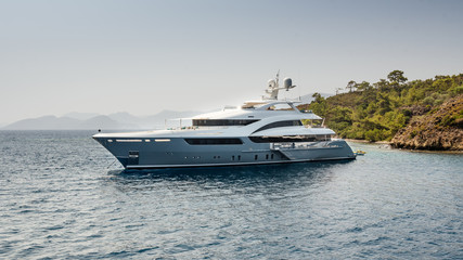 A large private luxurious modern private yacht around the island on a background of the sky - obrazy, fototapety, plakaty