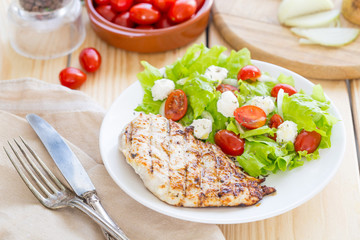 Marinated Grilled Healthy Chicken Breast served with Fresh Salad on a Wooden Background