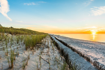 Sandy beach and sunset sky with golden sun shining on white sand