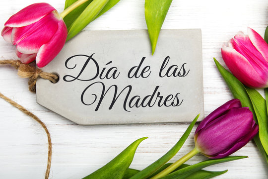 Mother's day card with Spanish words: Happy Mother's day, and  blue flowers frame on white wooden background