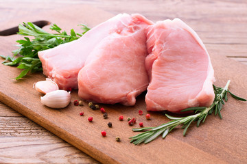 Raw pork meat with spices and vegetables on wooden desk close up, top view, horizontal