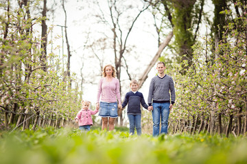 Happy young four member family standing together outdoors in orchard