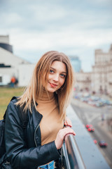 Portrait of joyful beautiful fashionable girl on roof . Beautiful city view