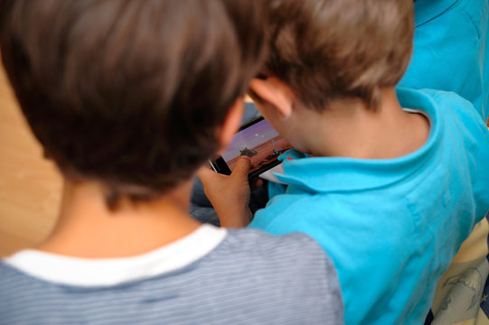 Jungs beim Spielen auf einem Smartphone &uuml;ber die Schulter geschaut
