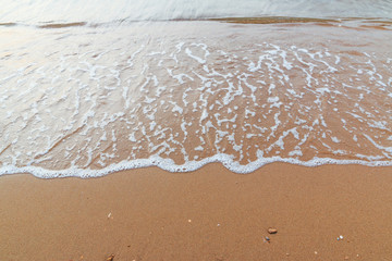 Soft white wave of  sea on sandy beach used as Background.