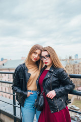 Fototapeta premium couple of women together in cityscape . Two joyful beautiful fashionable girls on roof . Beautiful city view