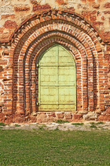 Old green arched door and red stone wall