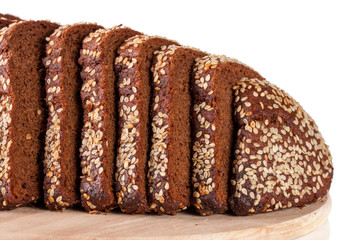 slices of black bread with sesame seeds on a cutting board isolated on white background