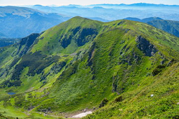 Fototapeta na wymiar Picturesque green ridge against the background of mountains