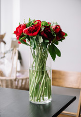 Beautiful Bunch of red peonies in a glass vase on the table in the florist shop. Beautiful Bunch of red peonies in a glass vase on the table in the florist shop