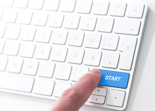 finger pressing a key labeled START on a computer keyboard