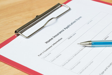Home insurance application form with red file on wooden table