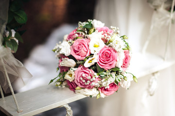 Wedding bouquet of white and pink roses on white wooden swing, a bouquet of the bride, close-up
